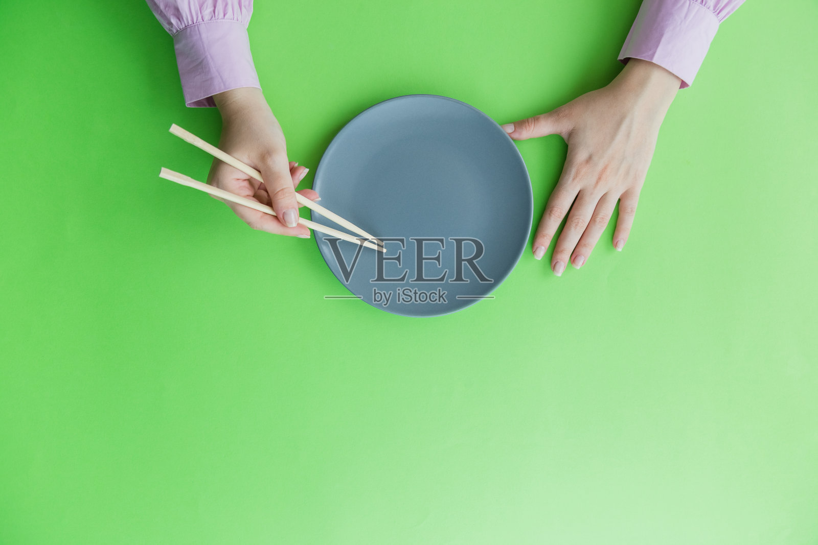 高角度的女人拿着筷子和盘子。日本或中国的食物概念。照片摄影图片