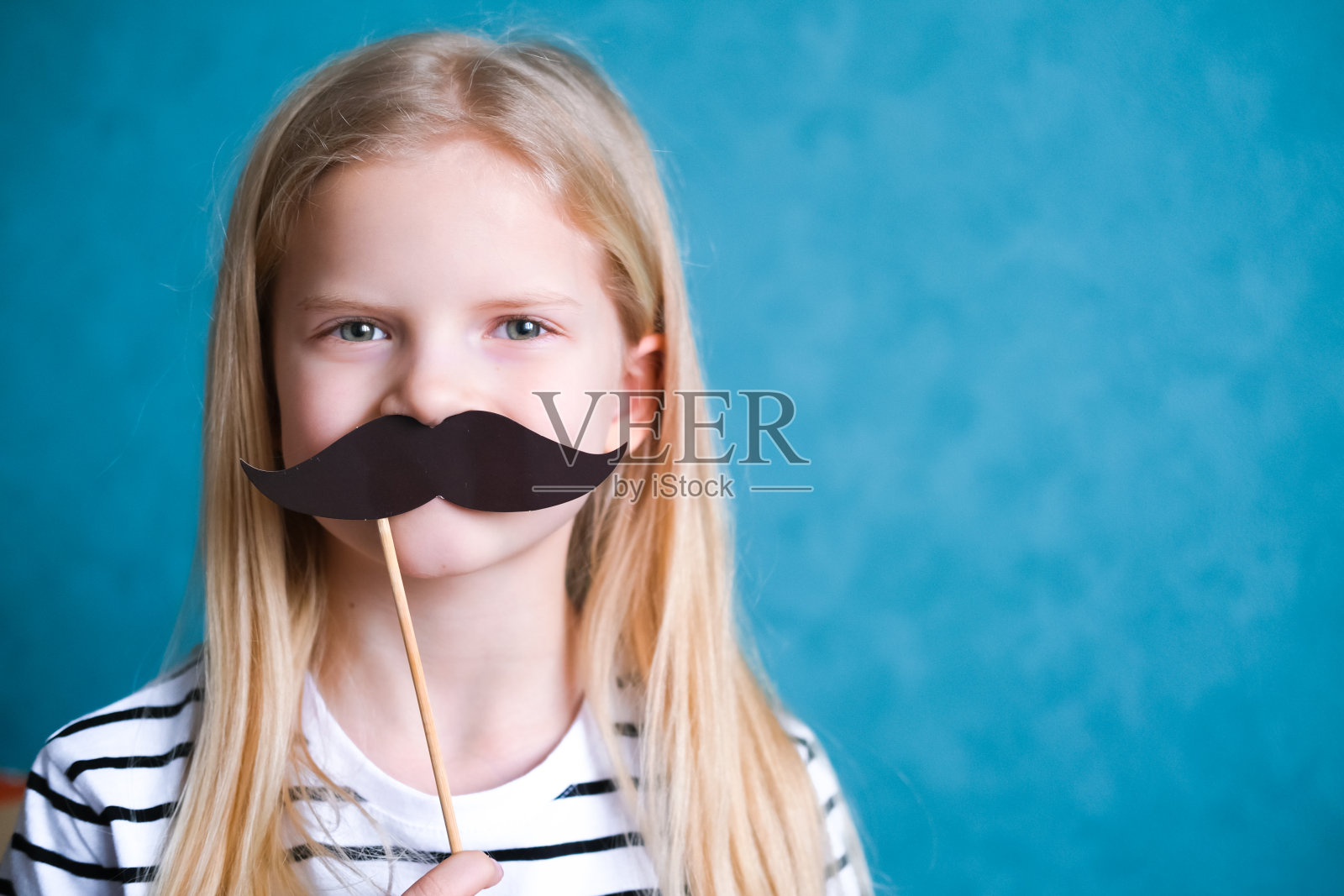 蓝色背景上留着小胡子的金发小女孩。Copyspace。父亲节快乐照片摄影图片