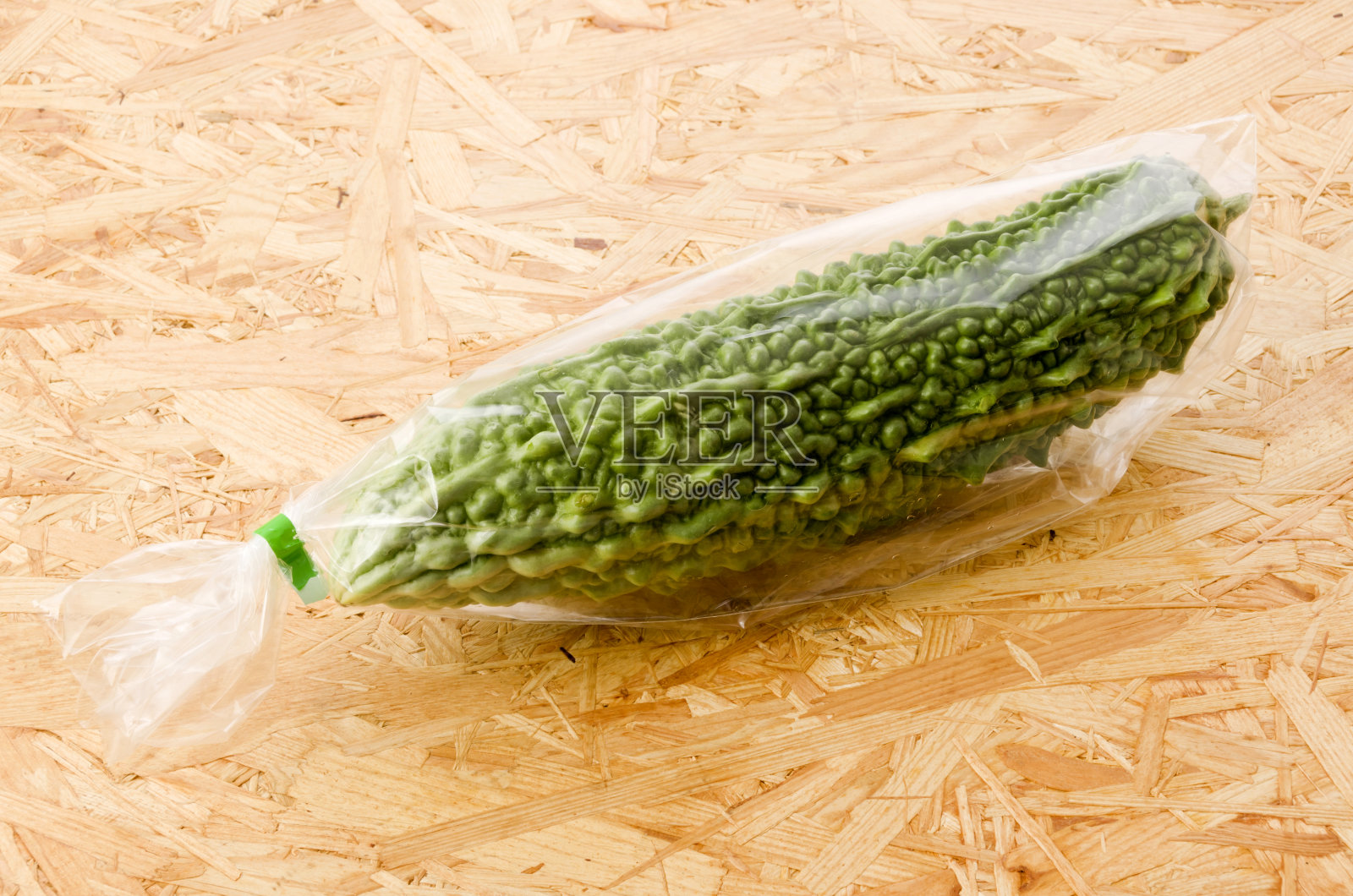 新鲜的戈雅，胶合板背景上的塑料苦瓜照片摄影图片