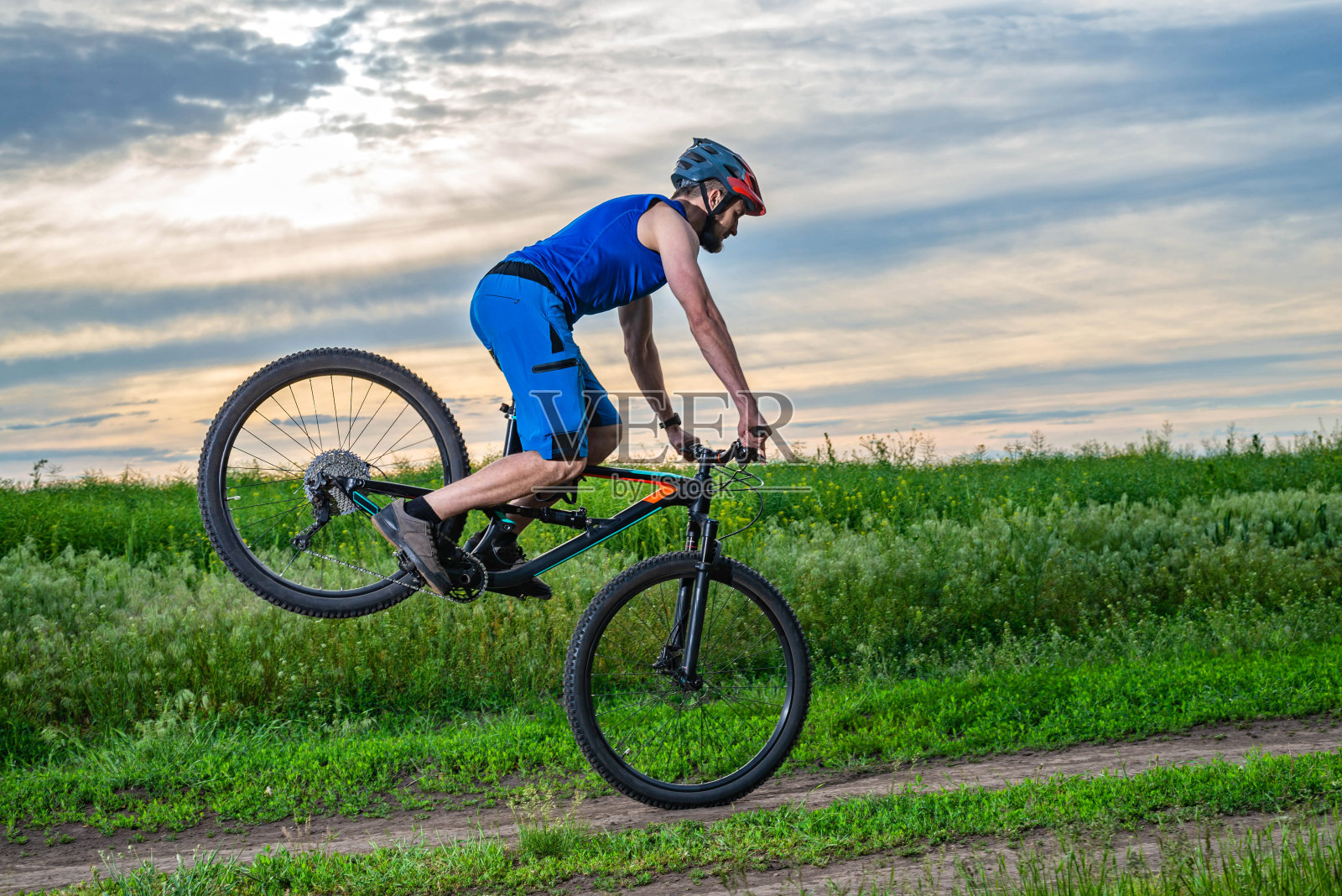 骑自行车的人戴着头盔站在自行车前轮上。照片摄影图片