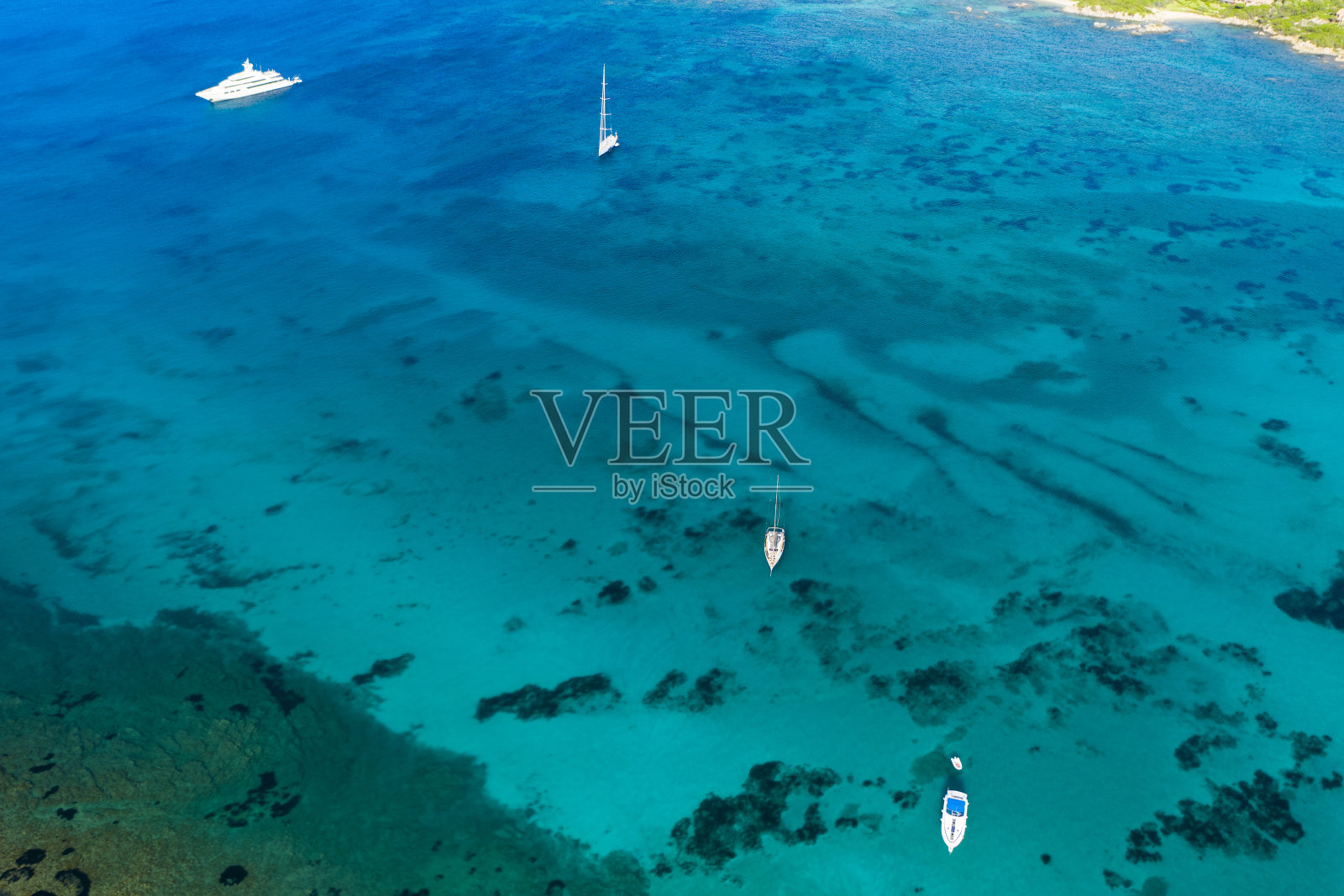 从上面俯瞰，一些游艇和帆船在美丽的绿松石海上航行的令人惊叹的鸟瞰图。意大利撒丁岛翡翠海岸的切尔沃港。照片摄影图片