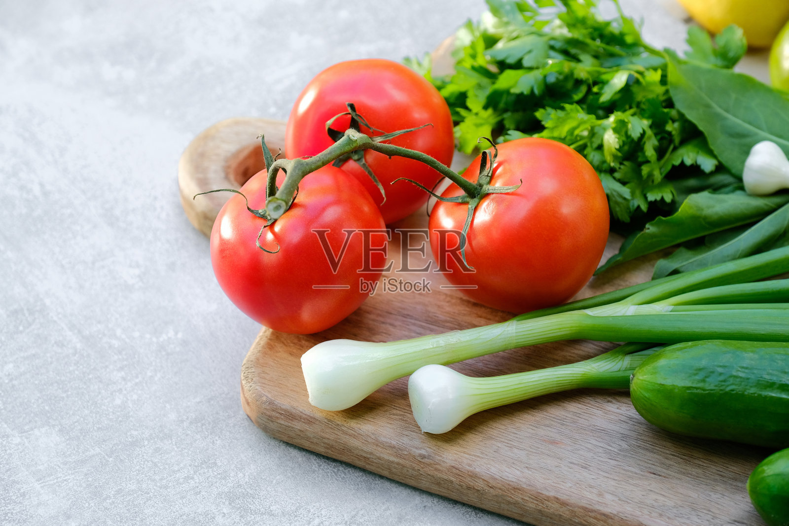 旧木砧板和新鲜蔬菜在石头混凝土桌上。近距离观看沙拉配料:西红柿，黄瓜，洋葱，欧芹照片摄影图片