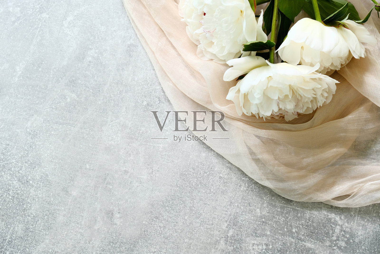 混凝土桌上摆着一束牡丹花和米色织物，从上面俯瞰。母亲节，妇女节，婚礼庆祝概念。照片摄影图片