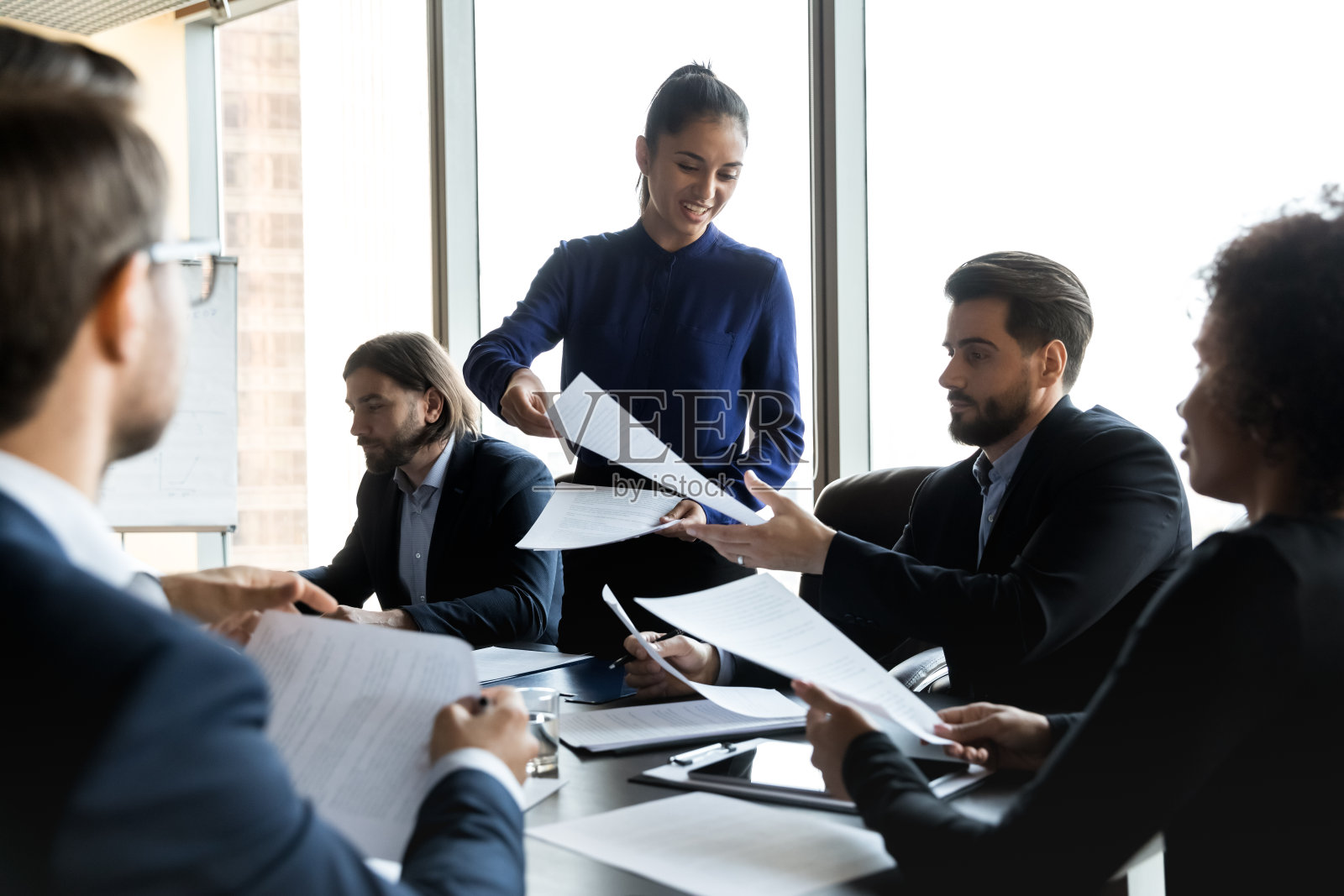 微笑的女商人教练在简报会上给员工分发材料照片摄影图片