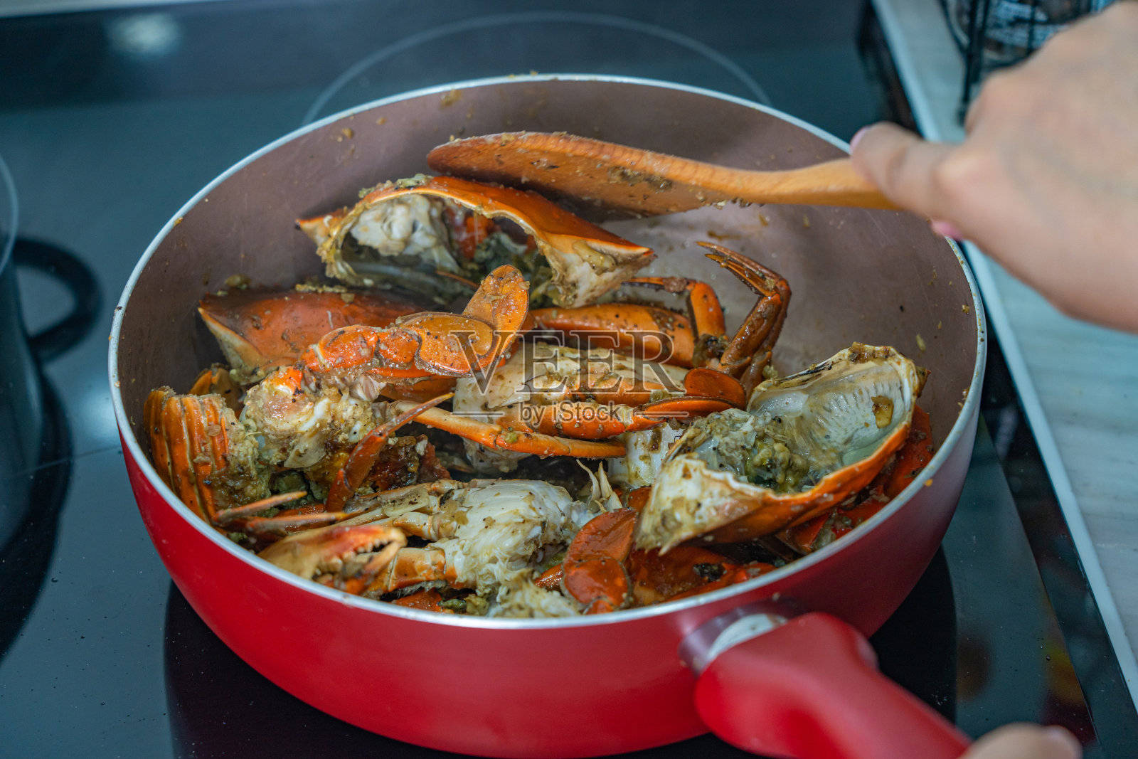 人的手用锅铲炒蟹照片摄影图片
