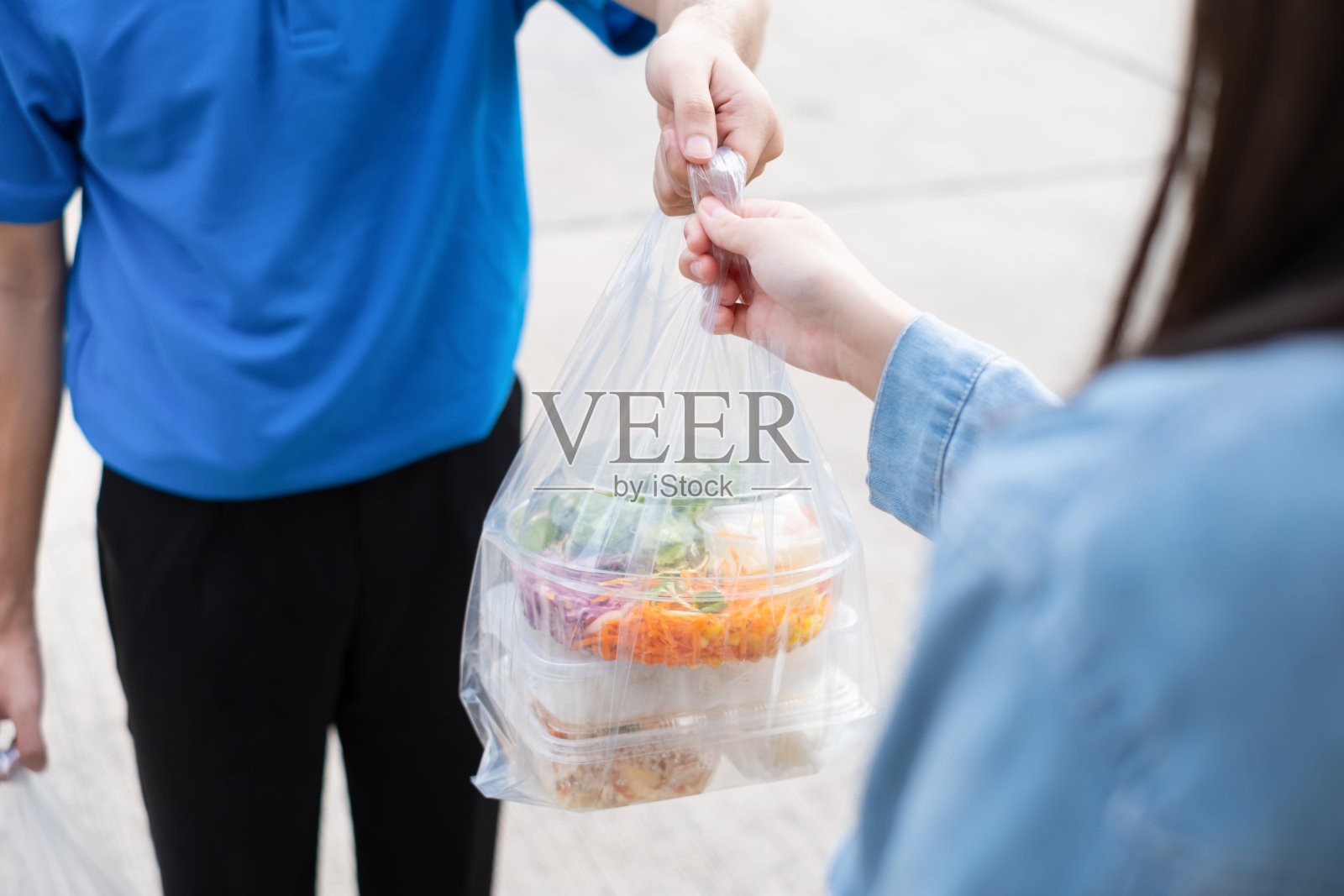 戴口罩的送餐员将网上购物的塑料袋从超市递至女性客户服务客户前台，快递杂货店时冠状病毒新冠肺炎的新常态生活方式。照片摄影图片