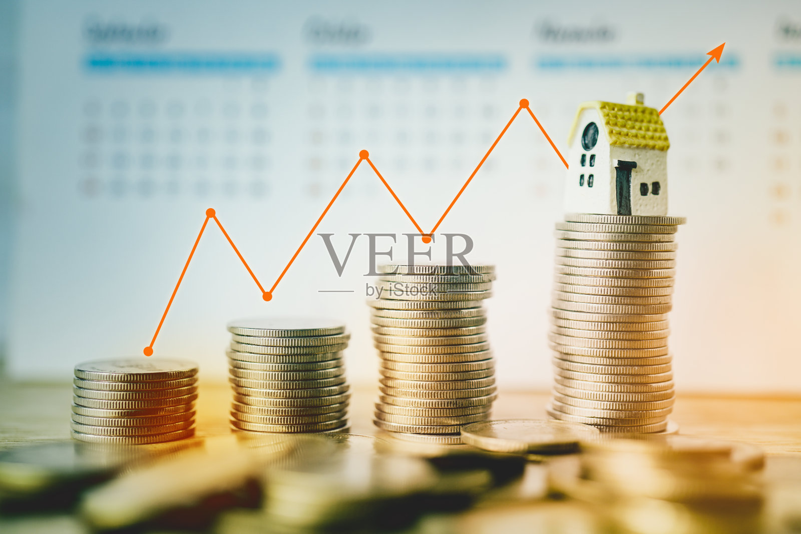 微型房子在一堆硬币模糊日历和橙色图形为商业和金融背景照片摄影图片