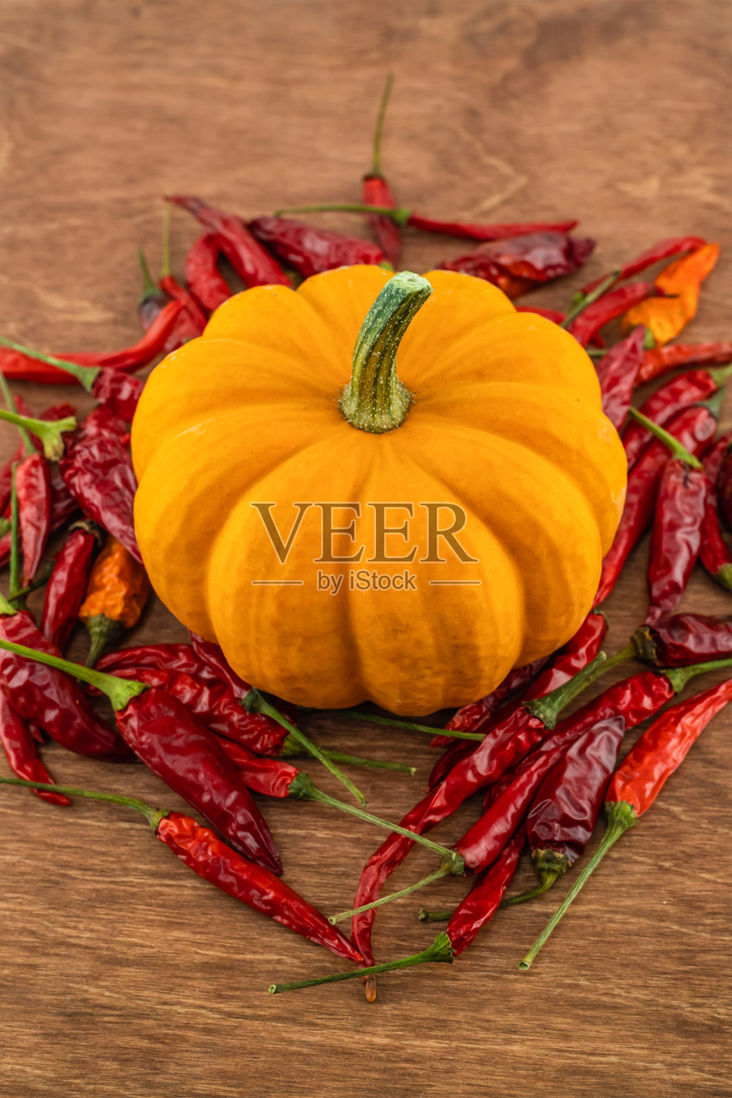 木制砧板上的小南瓜，周围环绕着红辣椒照片摄影图片