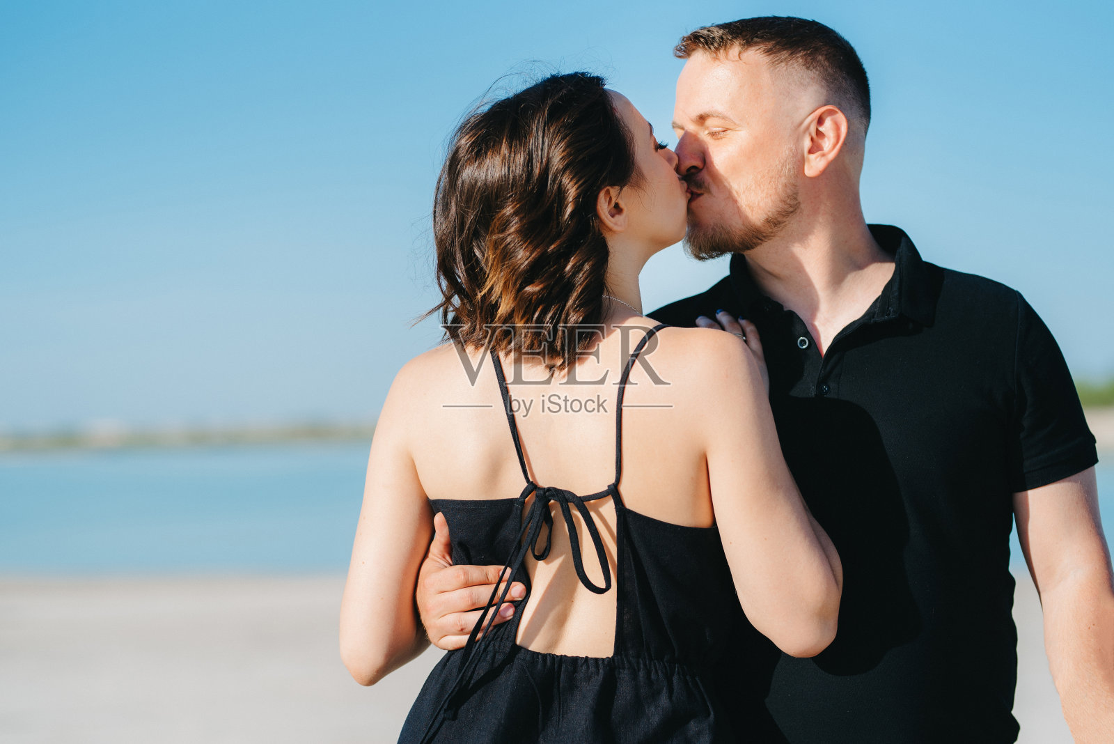 一对年轻夫妇一个男人和一个穿黑衣服的女孩走在白色的沙滩上照片摄影图片