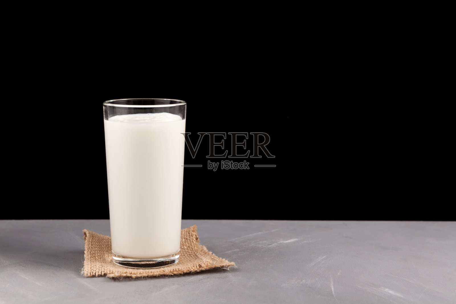 艾兰酒或开菲尔酒，在黑暗背景下的玻璃杯里。发酵的牛奶纯正。牛奶减肥食谱。有选择性的重点。文本的地方照片摄影图片