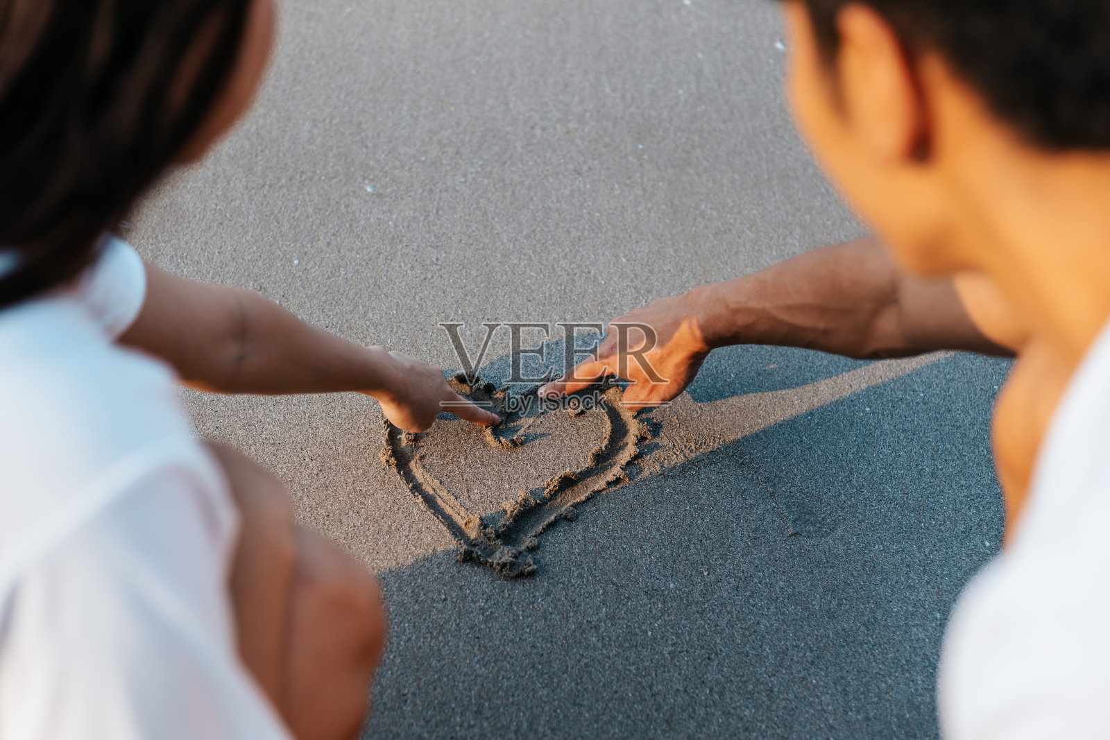 一对浪漫的情侣在沙滩上画心形。照片摄影图片