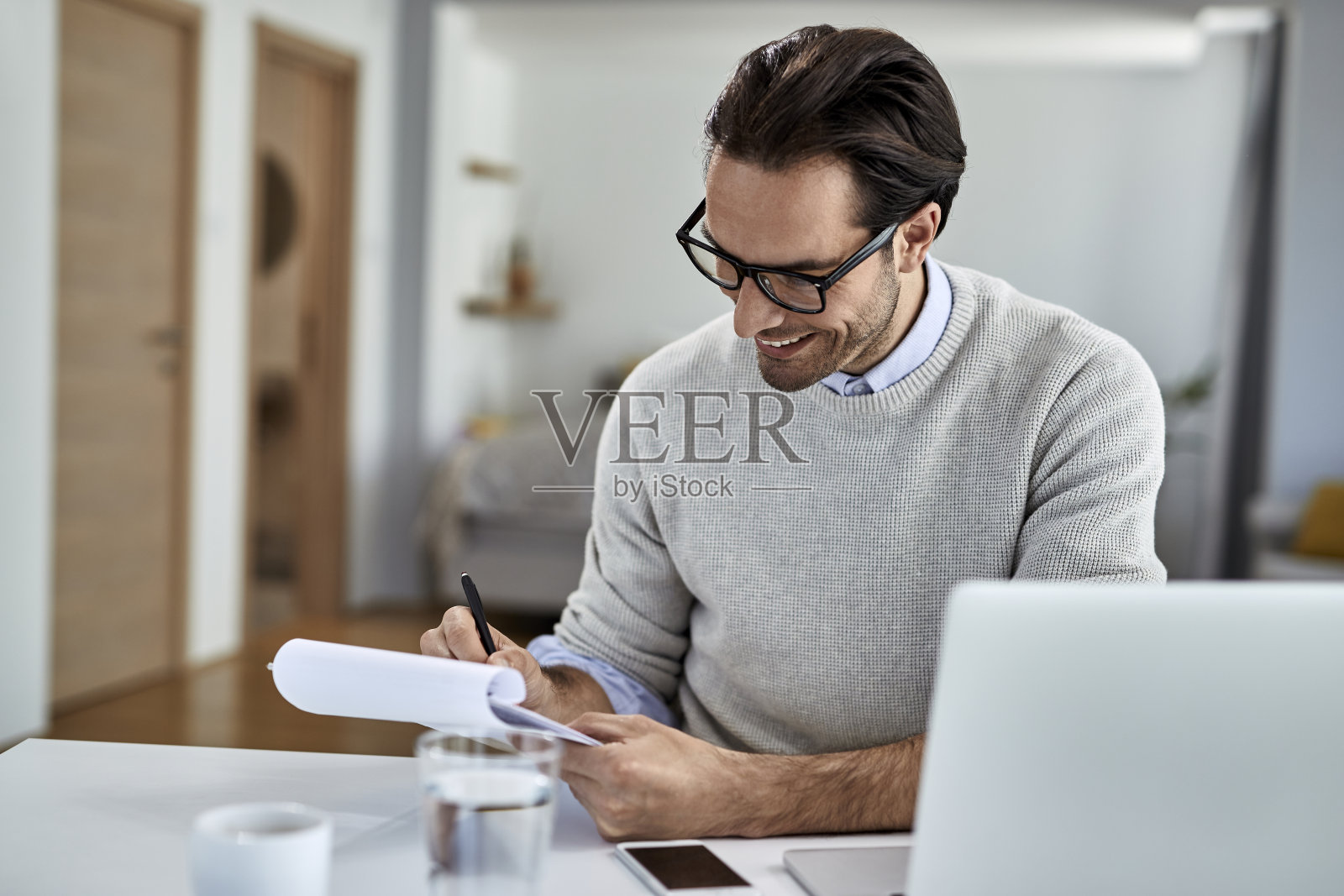 年轻快乐的企业家在家写商业报告。照片摄影图片