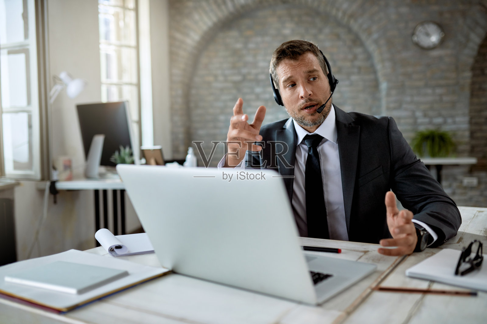 在办公室工作时使用笔记本电脑进行在线会议的商人。照片摄影图片