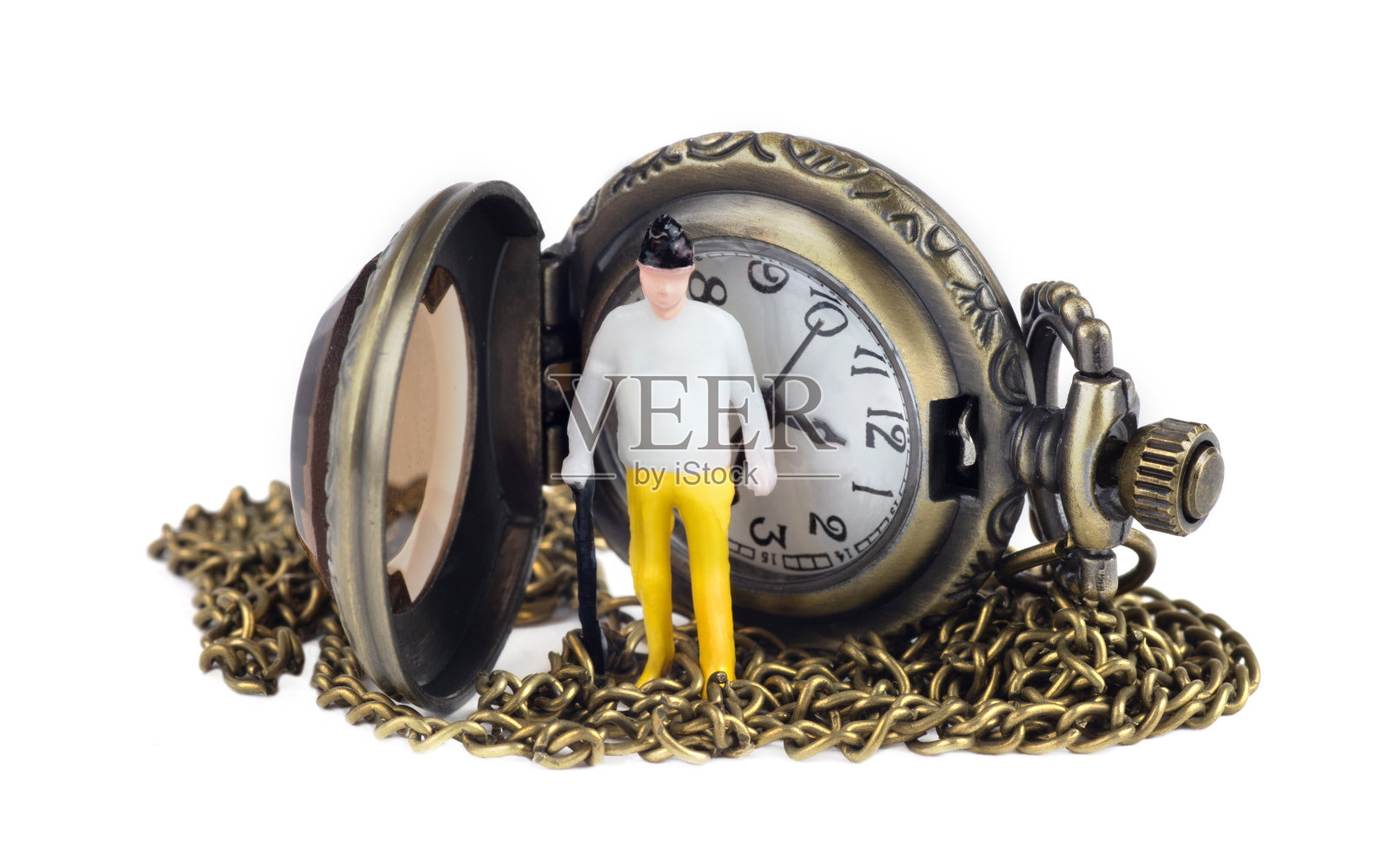 一个拄着拐杖的老人的玩具形象，站在一个打开的带链子的古董怀表前面。微距拍摄，在白色上孤立。照片摄影图片