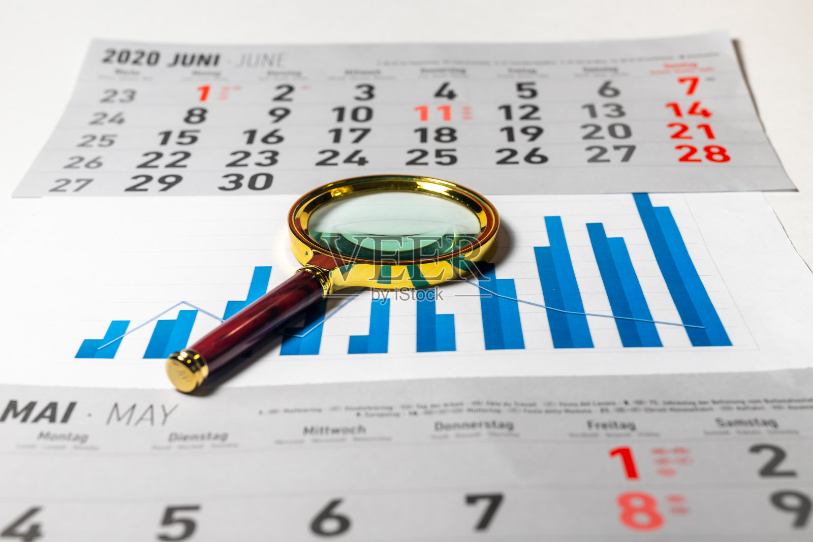 金色放大镜在图表图表的增长在蓝色颜色与日历表在蓝色表。数据分析的概念照片摄影图片