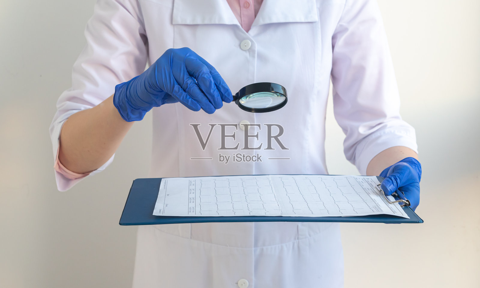 医生穿着工作服，戴着手套，通过放大镜分析病人的检查结果照片摄影图片