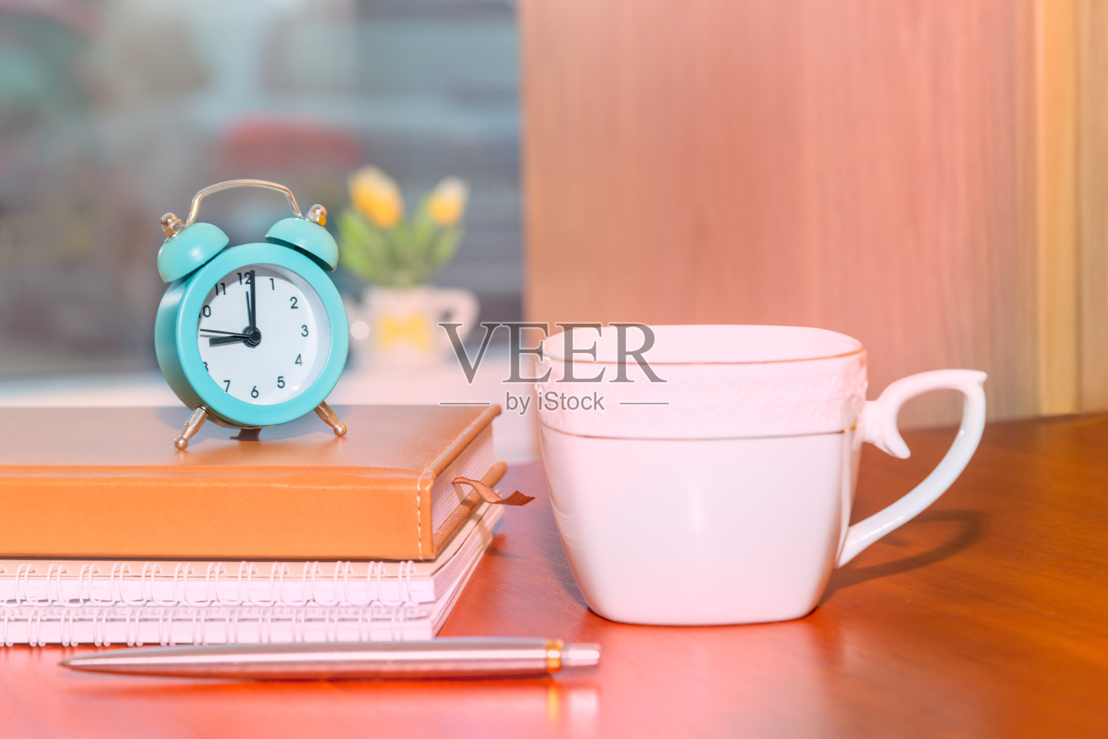 闹钟和文具放在书上，咖啡杯放在木桌上照片摄影图片