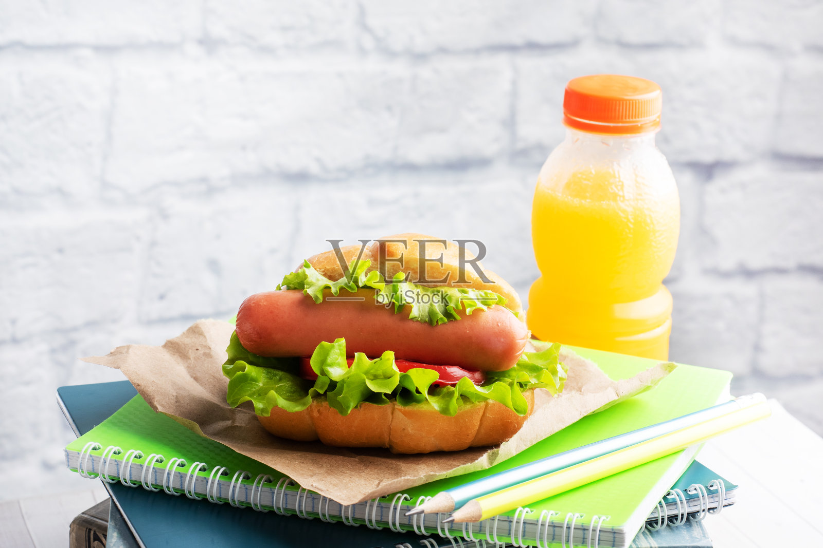 热狗加莴苣、蕃茄和香肠。笔记本和文具。学校的早餐概念。副本的空间。照片摄影图片