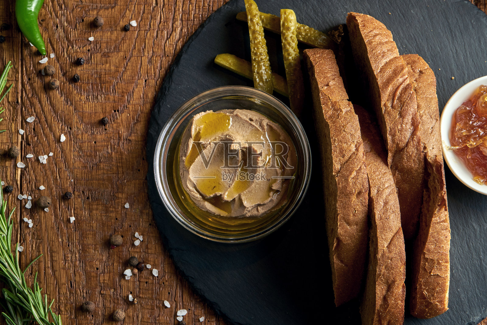 新鲜的自制鹅肝酱和黑麦面包放在黑色的盘子上，木制的背景。近距离品尝美味的餐厅食物。照片摄影图片