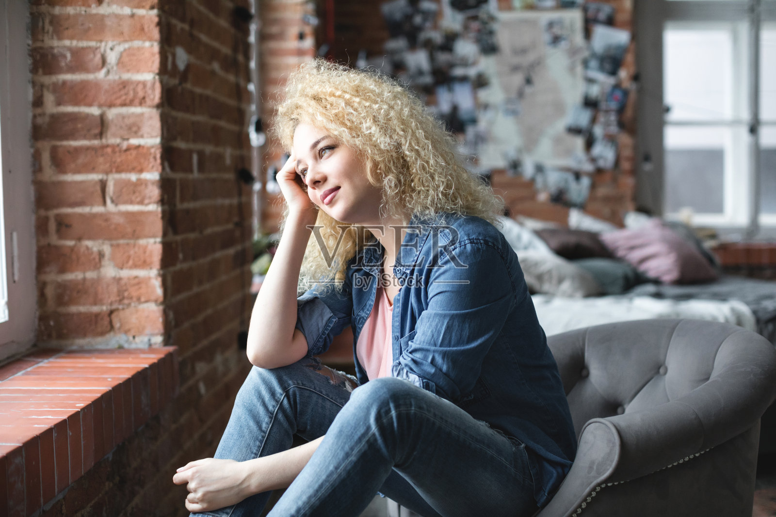 美丽的女人在家看着窗外。照片摄影图片
