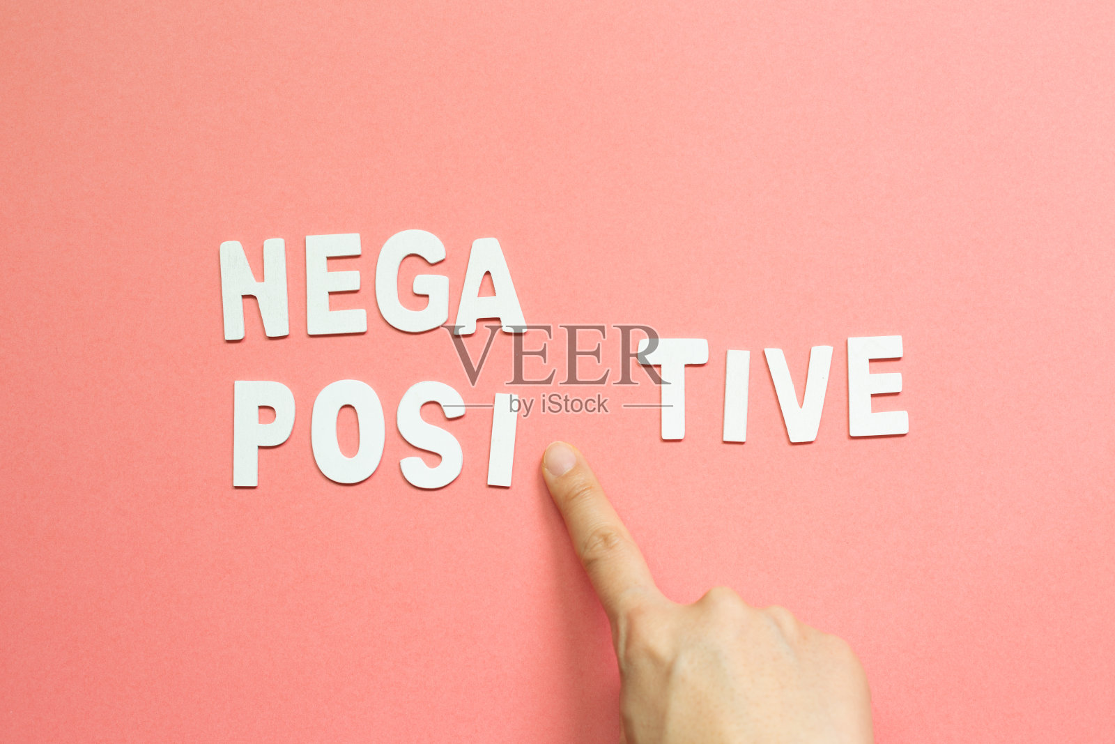 用手指在粉红色的背景上点一个“积极的”字。俯视图照片摄影图片