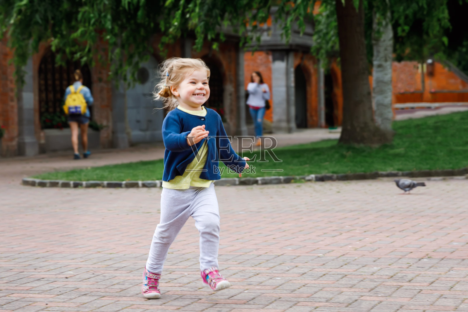 可爱的小女孩在爱尔兰都柏林的公园里奔跑。微笑和大笑的婴儿，孩子有乐趣，花在大自然的家庭度假。和小孩子一起旅行照片摄影图片