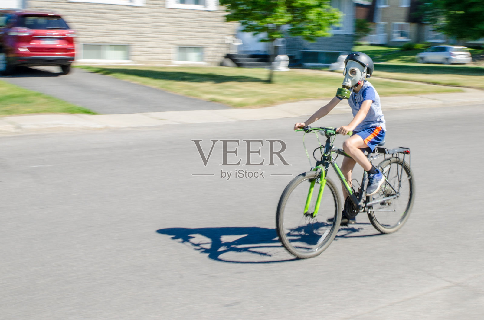 男孩骑着自行车带着防毒面具和头盔照片摄影图片