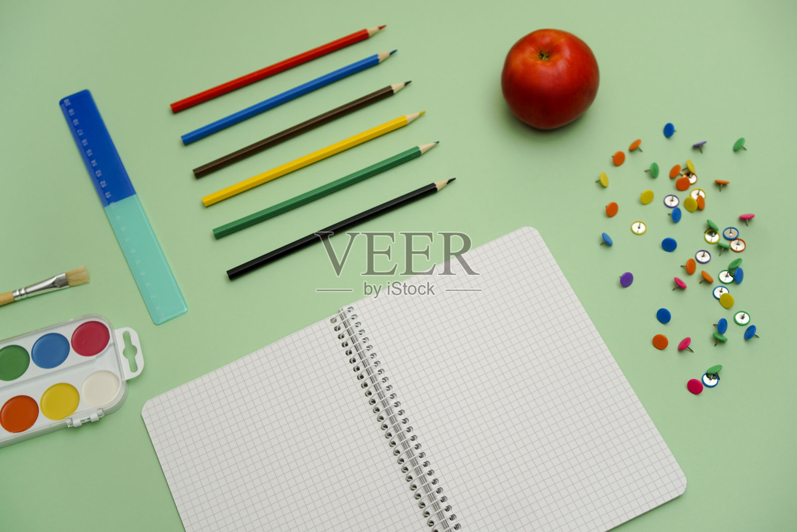 文具按钮和笔记本在绿色的表面用彩色铅笔照片摄影图片