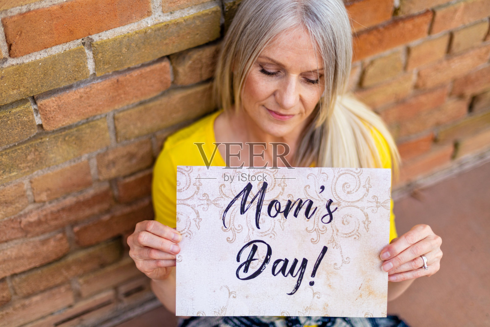 成熟的成年女性和手持式母亲节标志在充满活力的户外背景照片摄影图片