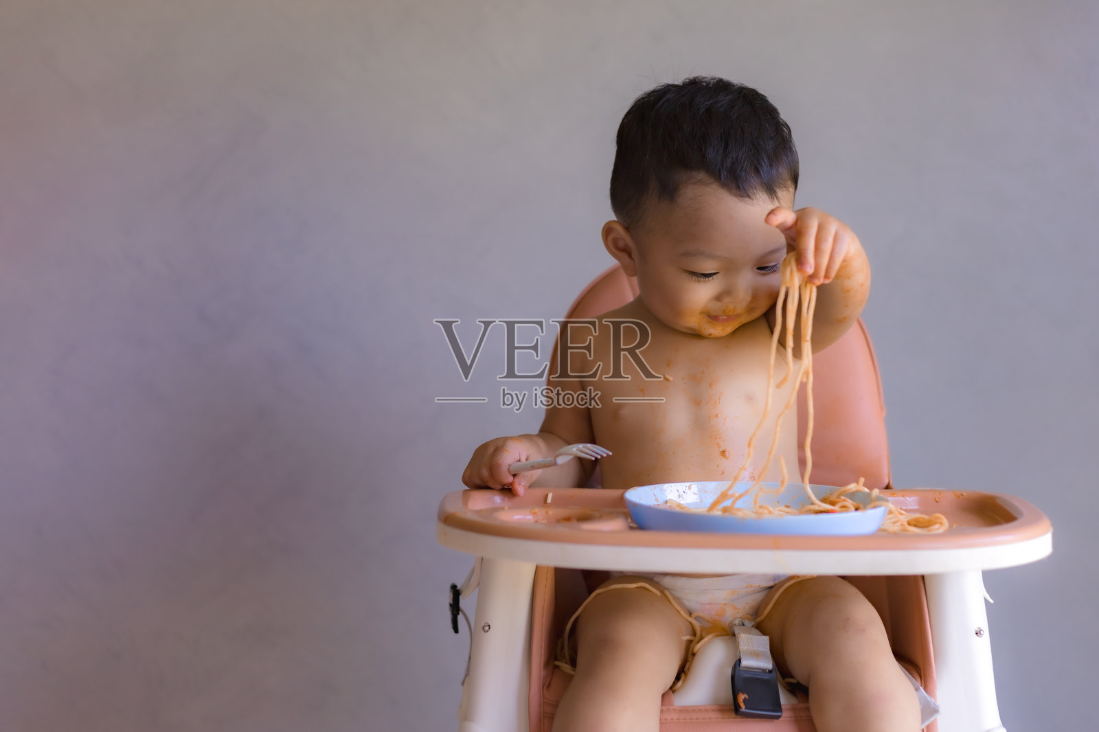 亚洲男孩吃高婴儿椅。照片摄影图片