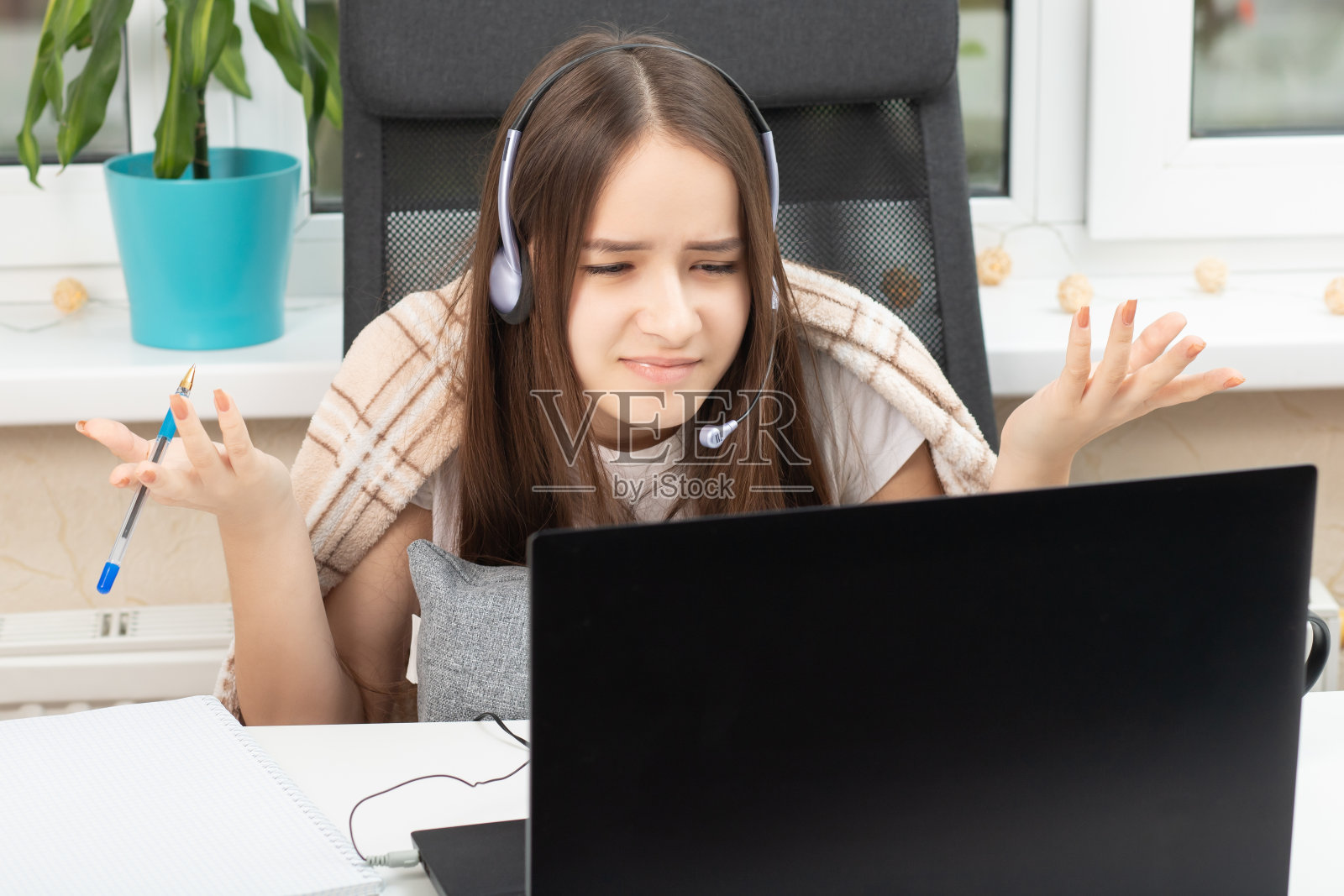 在线教育网络研讨会。学生在家里戴着耳机拿着麦克风在监视器前愤愤不平照片摄影图片