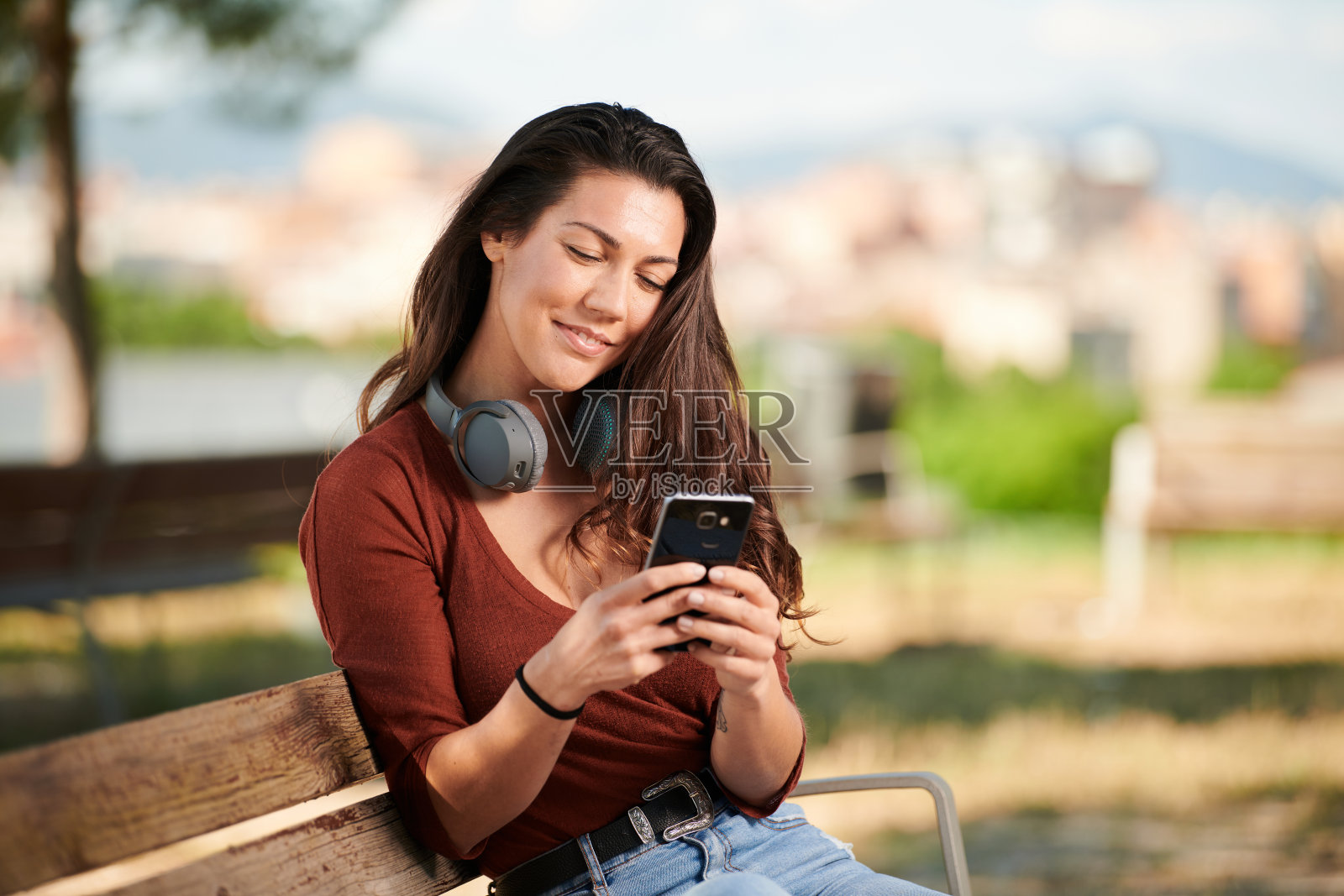 一个年轻女孩拿着手机坐在长凳上照片摄影图片
