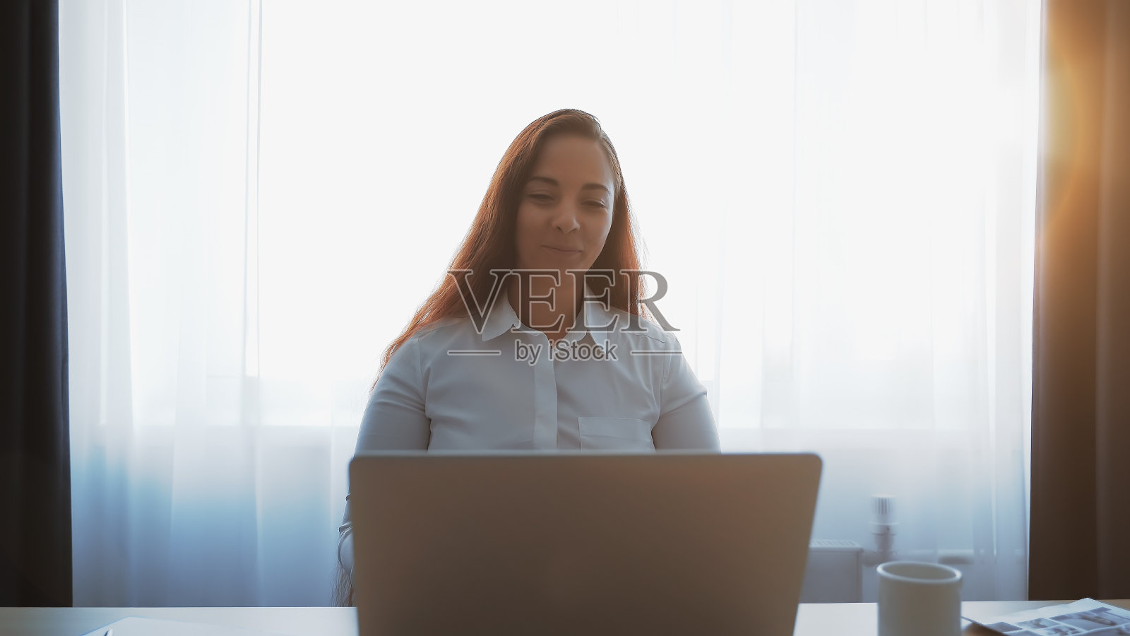 微笑的漂亮女孩使用笔记本电脑，看着屏幕，远程工作在线照片摄影图片