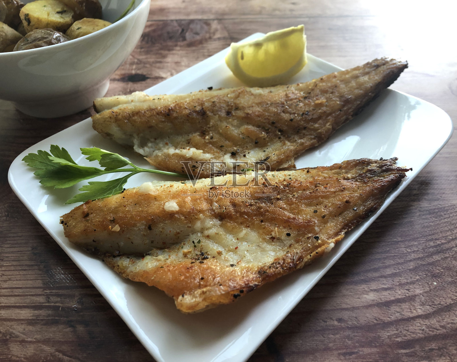 烤鲈鱼片配蒜汁和柠檬。照片摄影图片