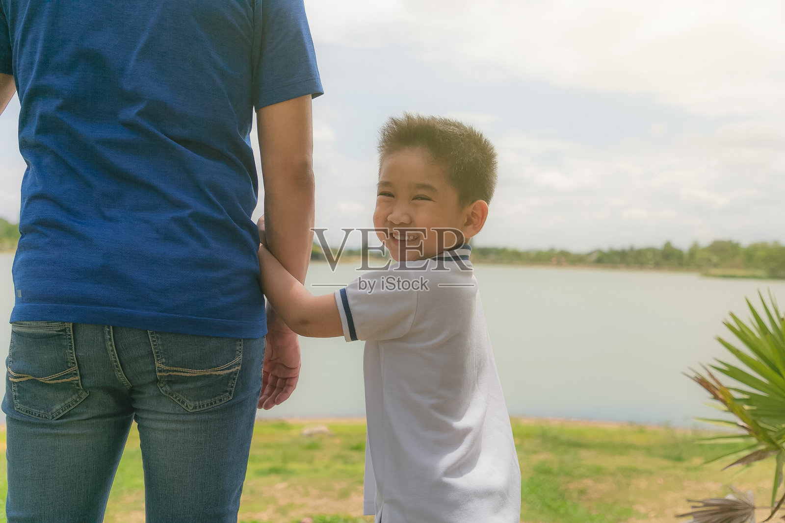 小男孩在公园外牵着爸爸的手拥抱。照片摄影图片