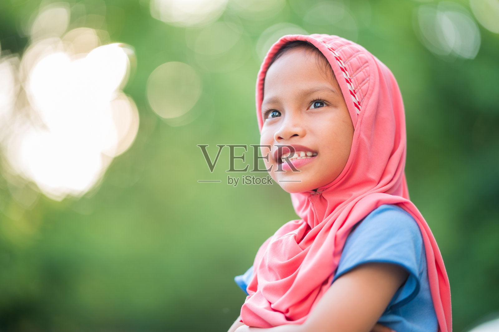一个年轻的穆斯林女孩的肖像，覆盖着红布看着镜头，微笑，快乐和复制空间照片摄影图片