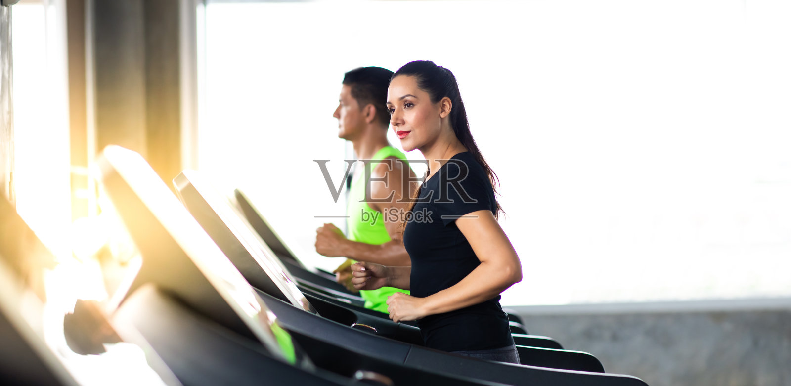 迷人的年轻女人和女性在跑步机上跑步在健身房体育俱乐部。健康的生活方式和健身理念。照片摄影图片