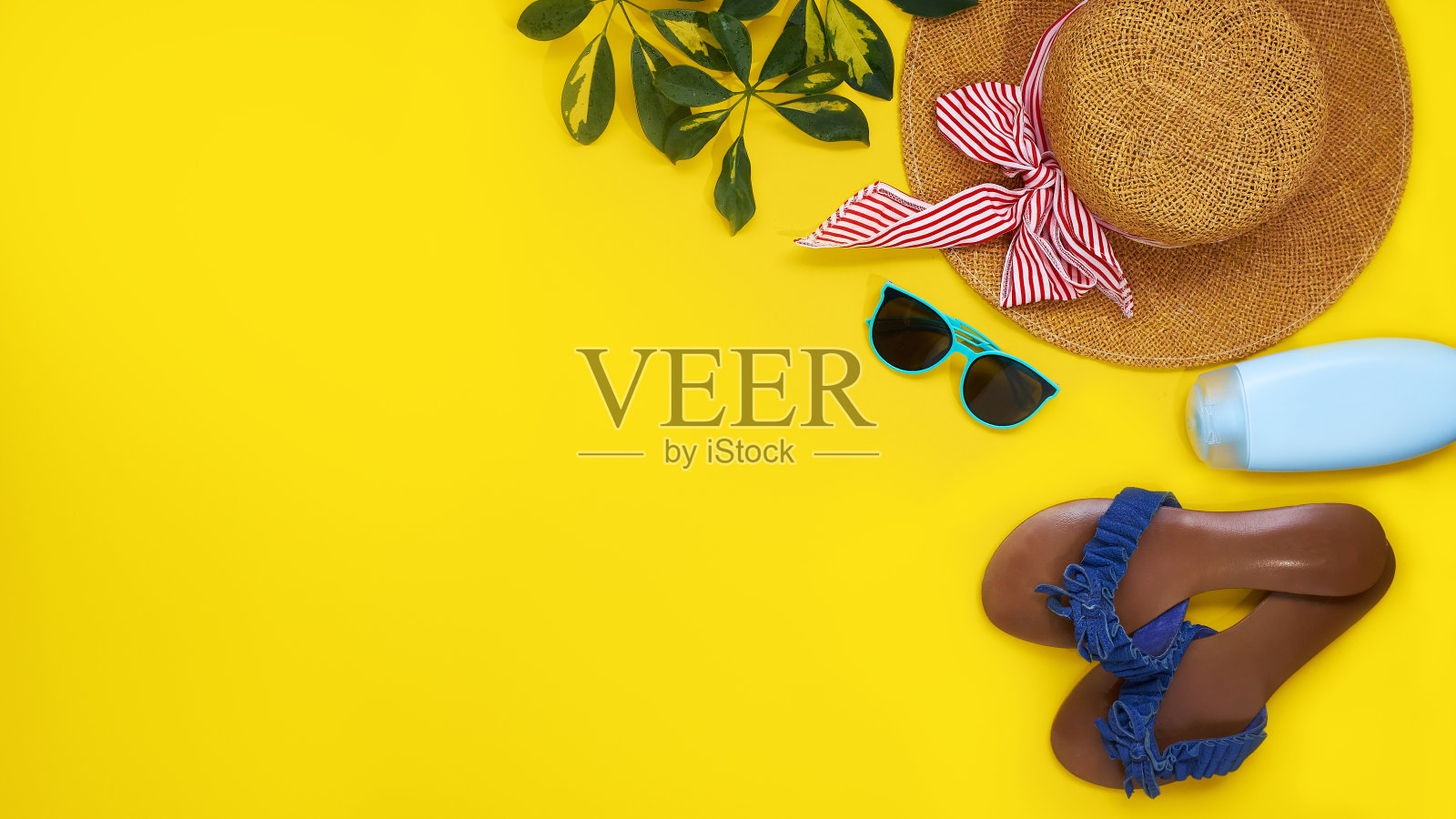 沙滩季的配饰。草帽，太阳镜，防晒霜和叶sheflers孤立在黄色背景。俯视图平铺照片摄影图片