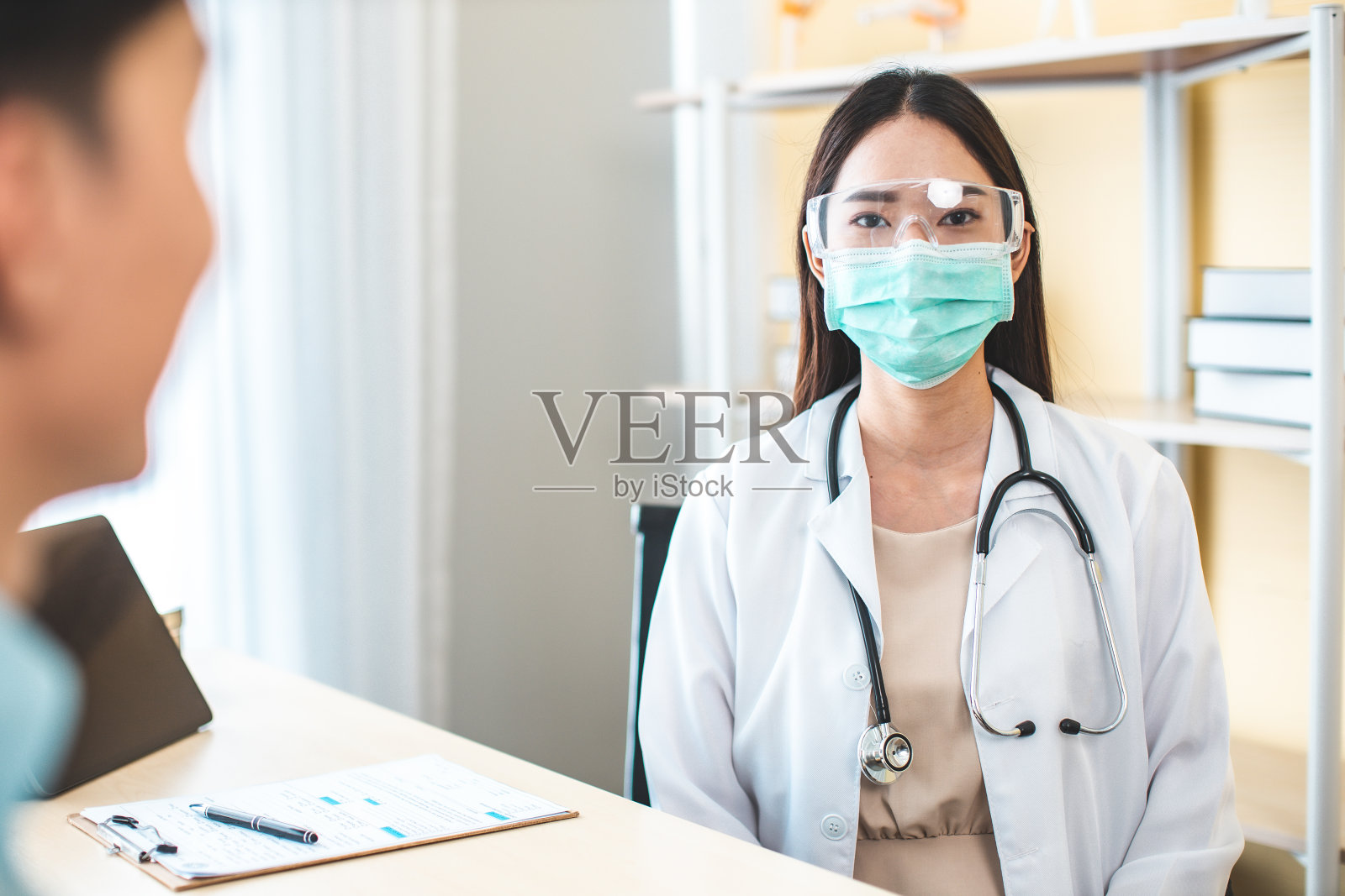 医学保健理念。亚洲女医生正在医院里照顾病人。医生或护士佩戴防护口罩检查和护理COVID-19感染者。照片摄影图片