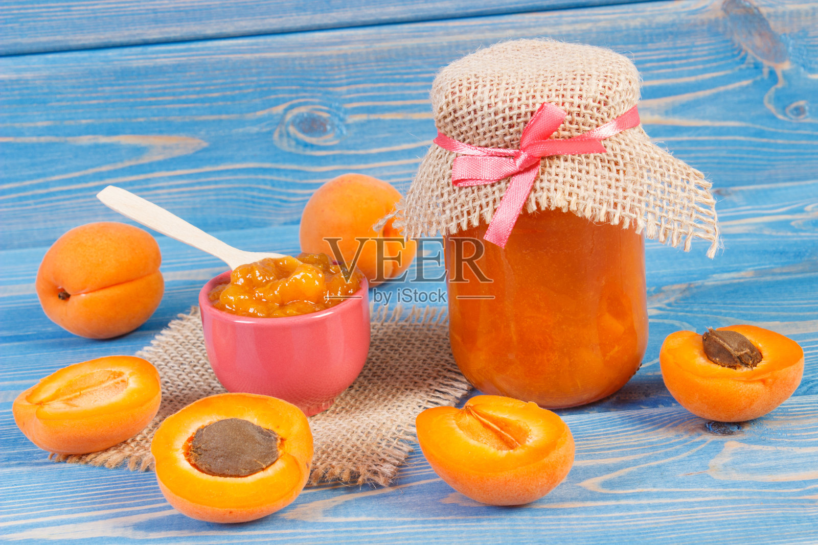 杏酱或果酱装在玻璃罐中，水果放在蓝板上，甜食的概念照片摄影图片