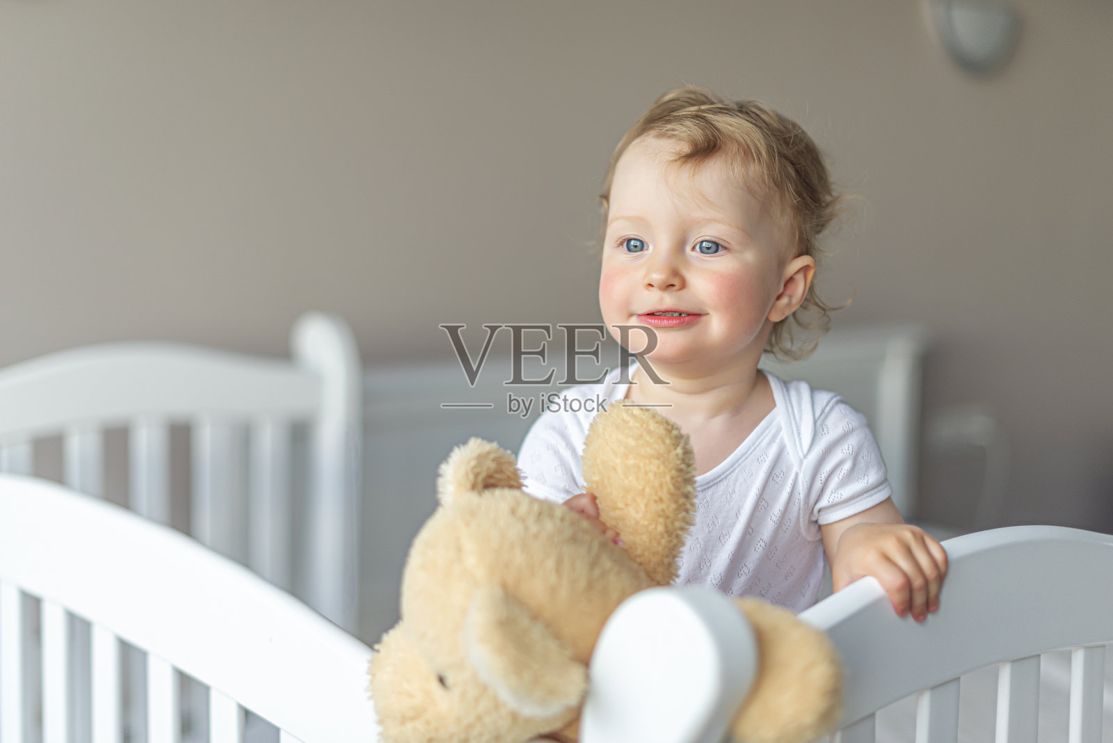 快乐的小女孩心情好地玩着泰迪熊。照片摄影图片