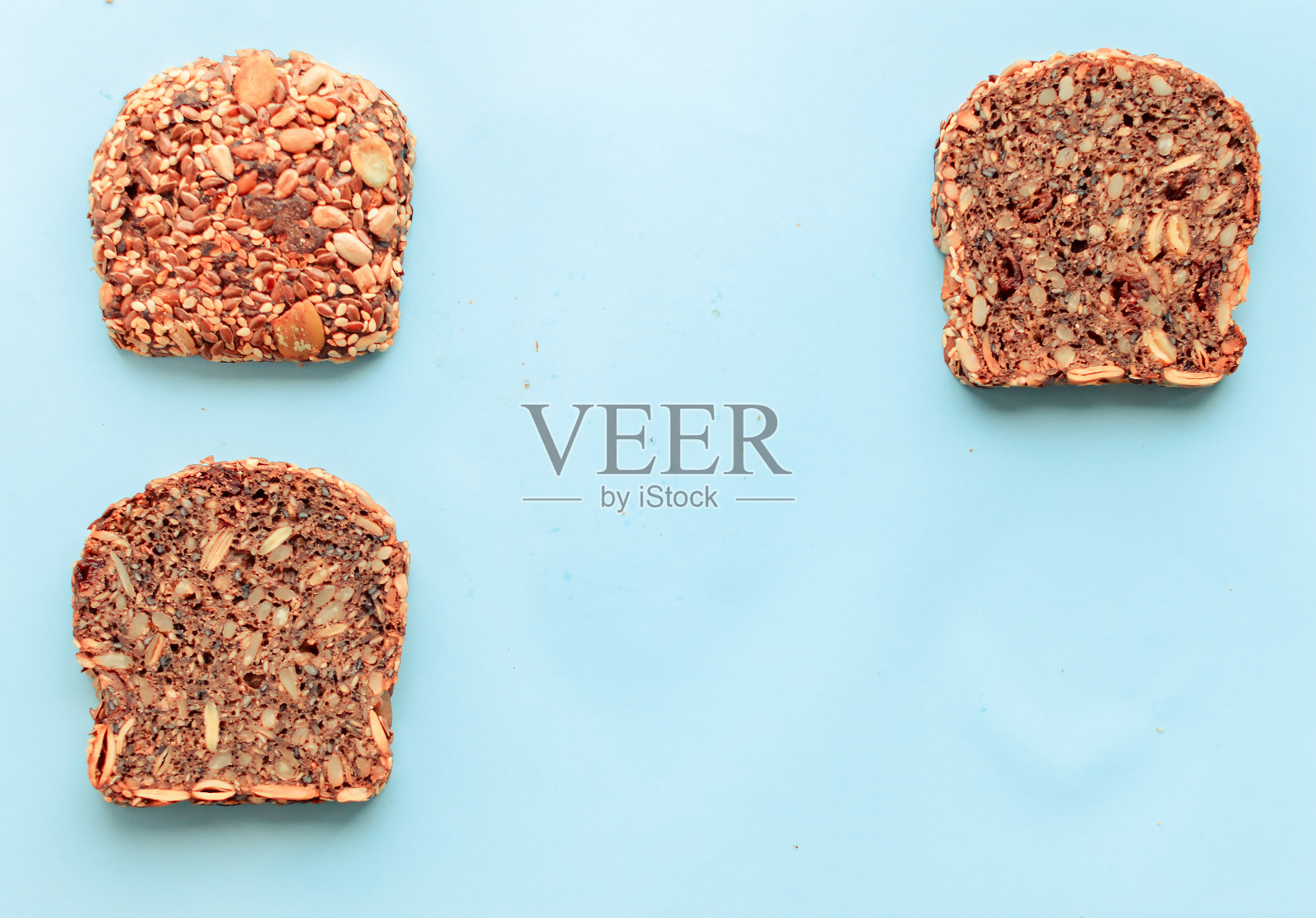 切成薄片的全麦面包，黑麦种子亚麻，向日葵，南瓜和芝麻。健康食品，环保天然产品。粉红色背景上的新鲜面包。照片摄影图片