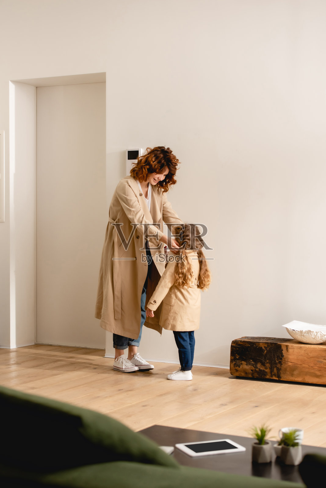 选择性的关注快乐的母亲看着女儿穿着风衣照片摄影图片