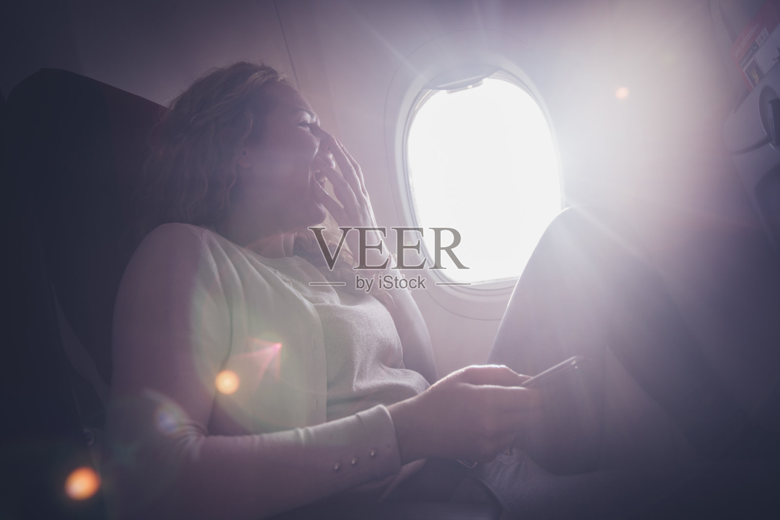 年轻的卷发女人打哈欠。照片摄影图片