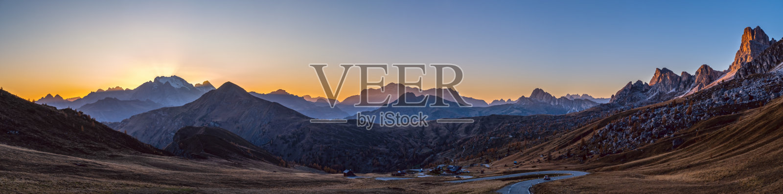 太阳在傍晚朦胧的天空中闪闪发光。从Giau Pass眺望宁静的山景。照片摄影图片