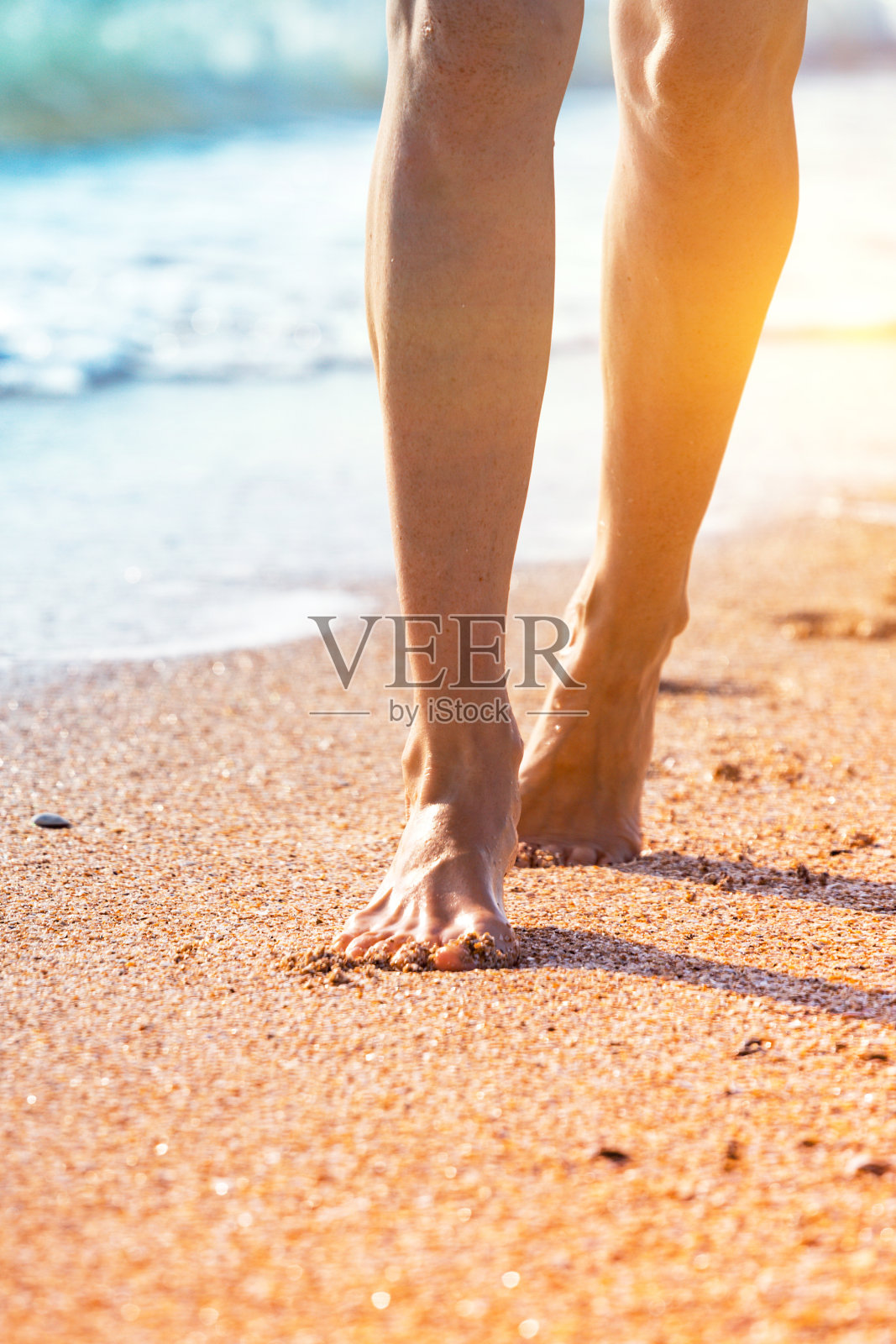 在夏天的海滩上，年轻女子沿着海浪的海水和沙子走着。旅行的概念。照片摄影图片