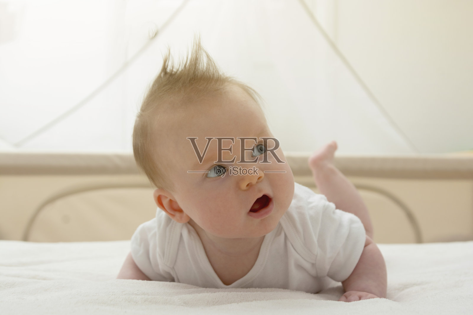 可爱快乐的新生婴儿正在学习坐在她的肚子上。蓝眼睛的微笑宝宝。照片摄影图片