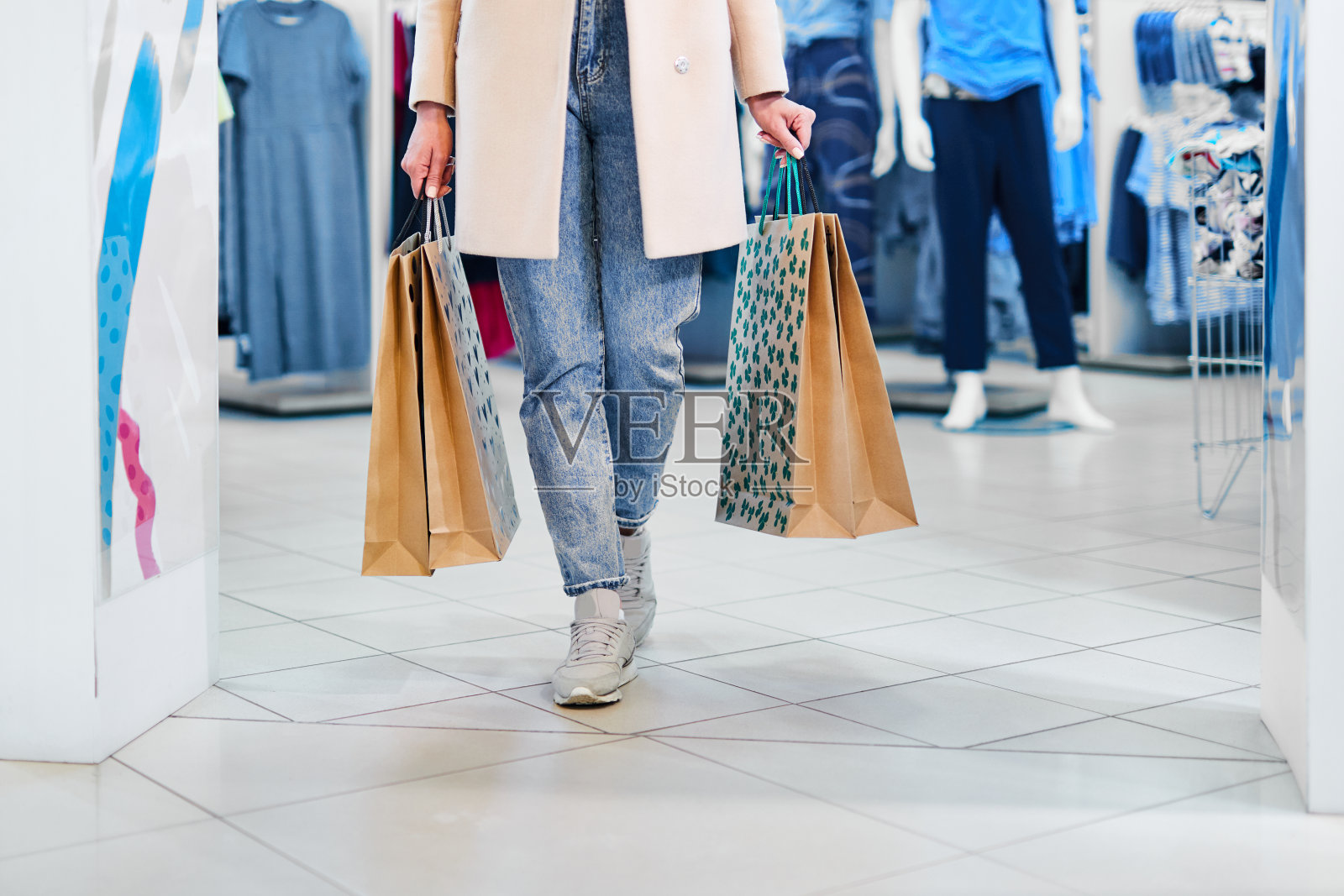 拎着纸袋走在现代商场里的女人。女孩提着购物袋在商店里散步。照片摄影图片