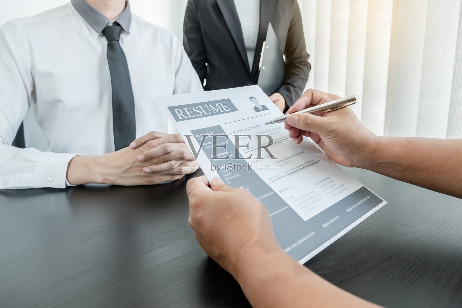 商务人士持有一份工作概况，并在工作面试中与求职者谈论职业和商业概念照片摄影图片