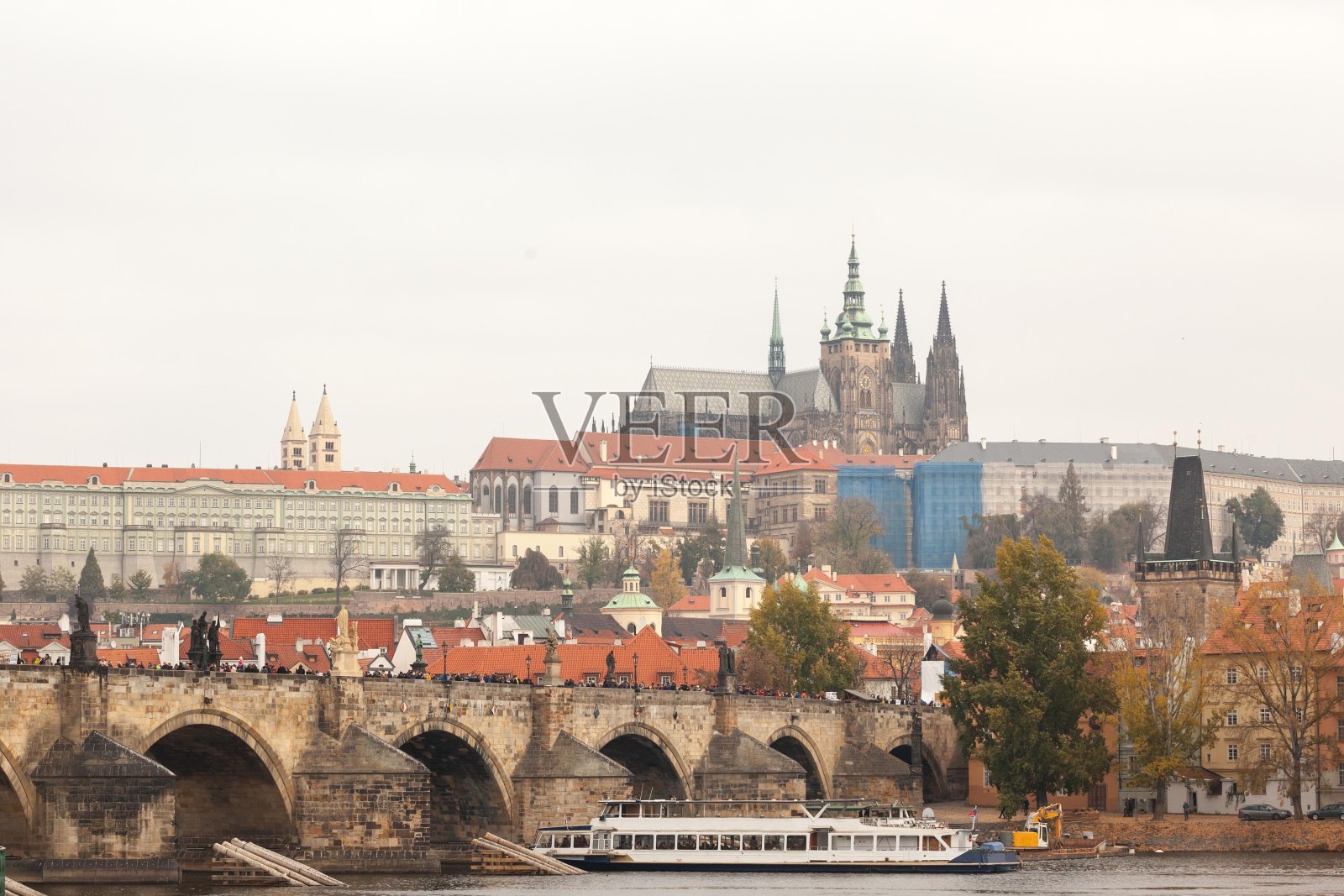 查尔斯桥(Karluv Most)和布拉格城堡(Prazsky had)从伏尔塔瓦河上看到一艘游船经过。这座城堡是这个城市的主要旅游标志。照片摄影图片